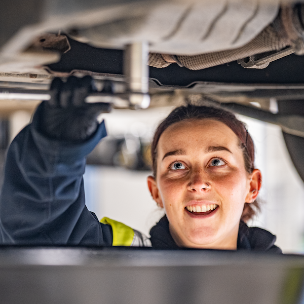 Female mechanic working underneath car