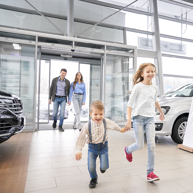 Happy family running into car dealership
