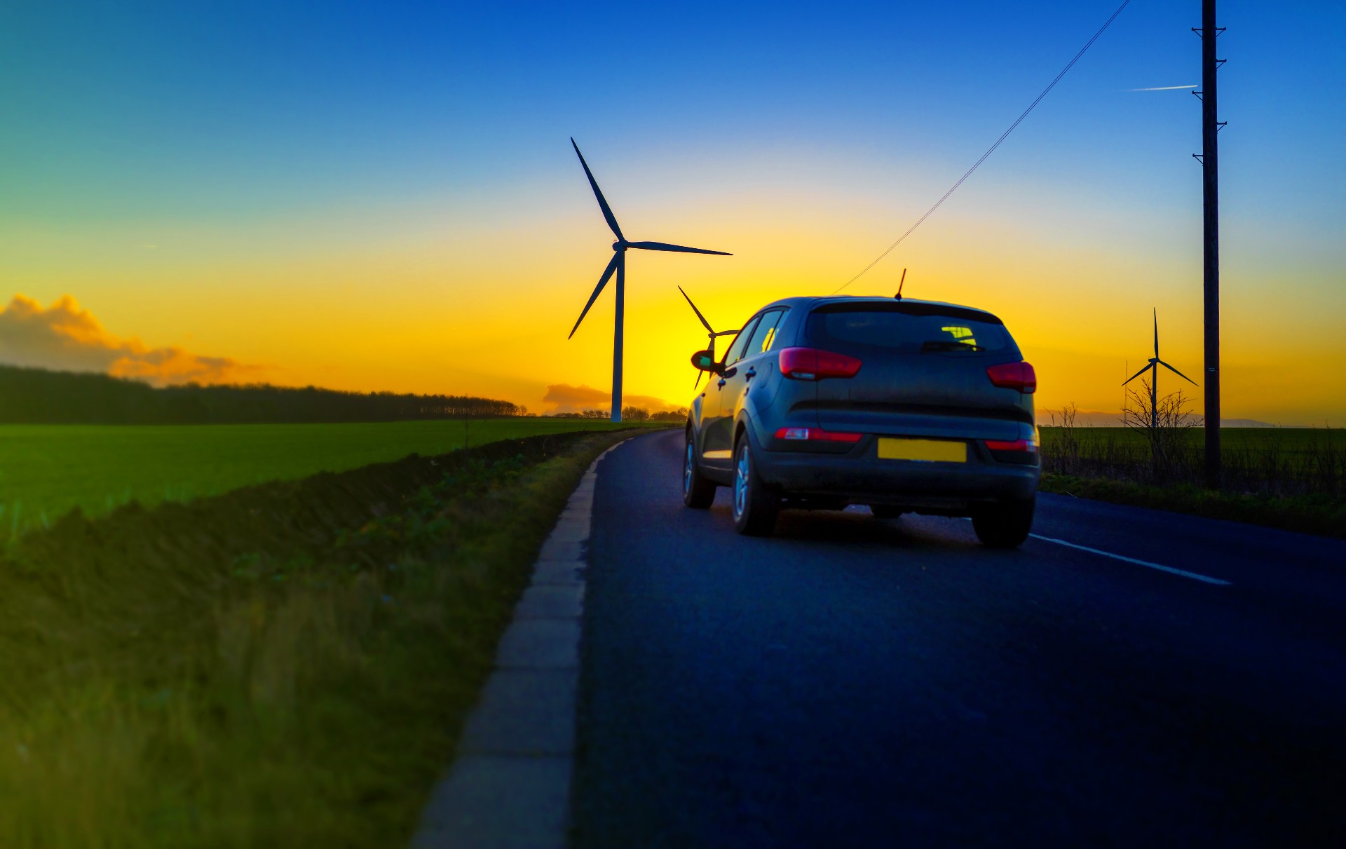 EV on road with wind turbine