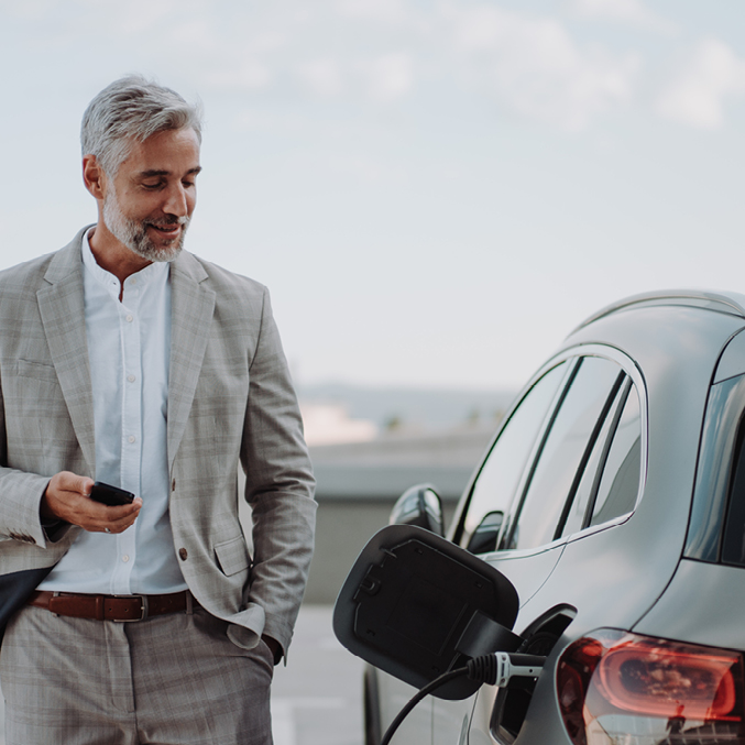 A man in a suit stood next to an electric vehicle charging