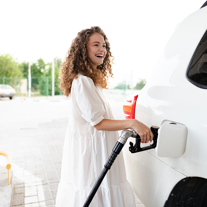 A smiling woman filling her car with fuel